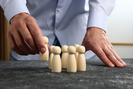Man with human figures at black table, closeupの写真素材