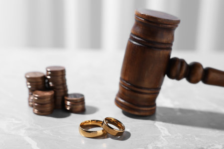 Alimony. Gavel, wedding rings and coins on gray marble table, closeupの写真素材