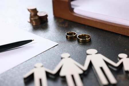 Alimony. Figures of family, wedding rings, pen, documents and coins on dark table, closeupの写真素材