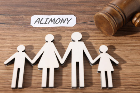 Paper note with word Alimony, judge's gavel and figures of family on wooden table, above viewの写真素材