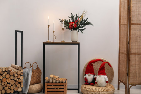 Christmas decor on console table and firewood near white wall indoors. Interior designの写真素材
