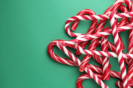 Pile of candy canes on green background, top view with space for text. Christmas treatの写真素材