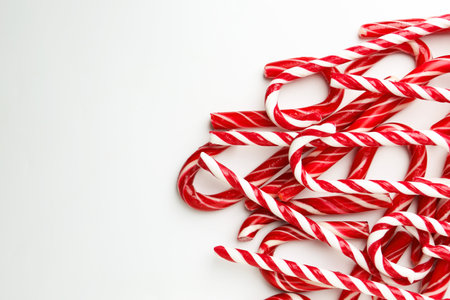 Pile of candy canes on white background, top view with space for text. Christmas treat