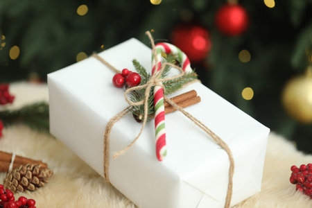 Decorated Christmas gift with candy cane on rug against blurred lights, closeupの写真素材