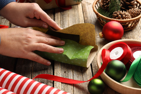 Woman wrapping Christmas gift at wooden table, closeupの写真素材