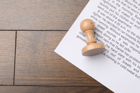 One wooden stamp and sheet of paper with text on table, top view. Space for text