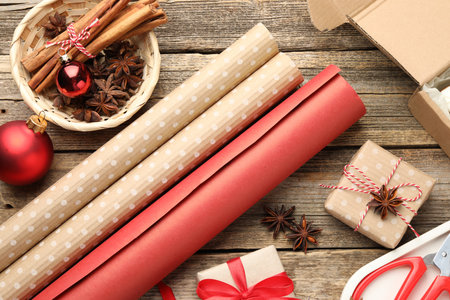 Festive packaging. Gift boxes, wrapping paper, baubles and spices on wooden table, flat lay. Merry Christmas and Happy New Yearの写真素材