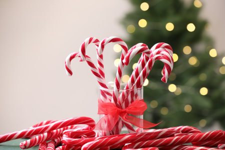 Candy canes on table against blurred lights, closeup. Christmas treat