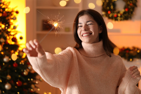 Happy woman with sparkler celebrating Christmas at home, bokeh lightsの写真素材