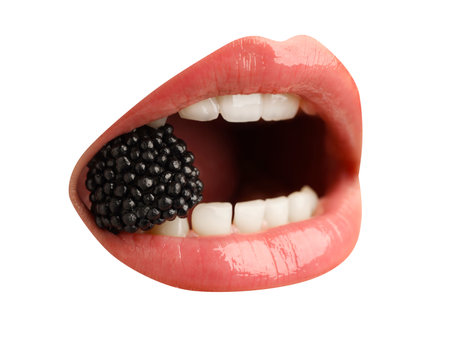 Woman with color lips holding fresh blackberry in her mouth on white background, closeupの写真素材