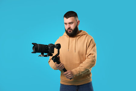 Videographer using gimbal stabilizer with camera on light blue background