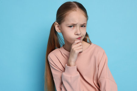 Portrait of cute girl on light blue backgroundの写真素材