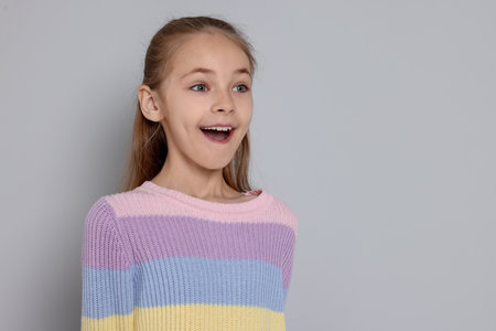 Portrait of cute girl on gray background, space for textの写真素材