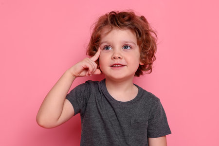Portrait of cute little boy on pink background