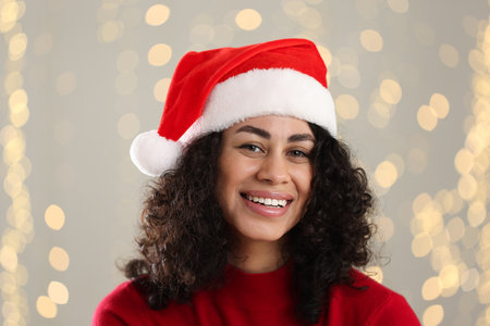 Portrait of attractive woman wearing Santa hat against blurred lights. Christmas seasonの写真素材