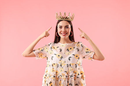 Beautiful woman wearing luxury crown on pink backgroundの写真素材