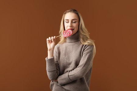 Christmas celebration. Woman with lollipop on brown backgroundの写真素材