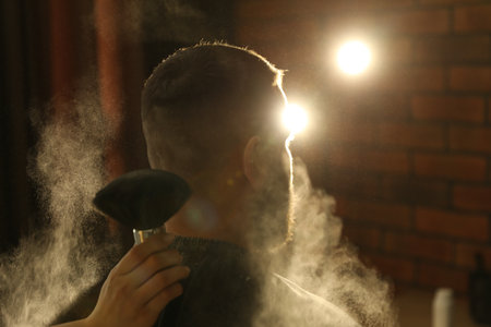 Hairstylist applying powder with brush onto man's neck at salon, closeupの写真素材