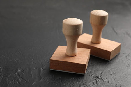 Two wooden stamps on dark textured table, closeup. Space for textの写真素材