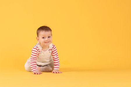 Cute little baby crawling on yellow background