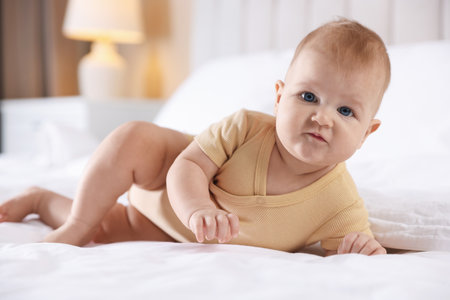 Cute baby with feeding bottle on bed at homeの写真素材