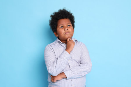 Portrait of cute little boy on light blue backgroundの写真素材
