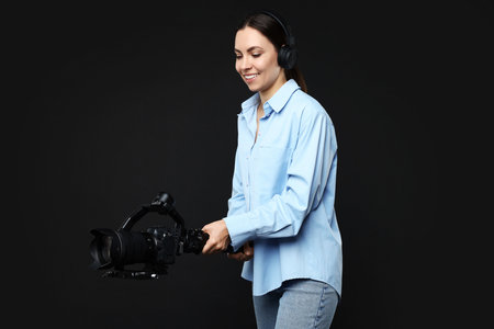 Videographer using gimbal stabilizer with camera on black background