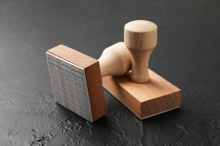 Two wooden stamps on dark textured table, closeup