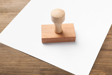 One wooden stamp and blank sheet of paper on table, closeup. Space for textの写真素材