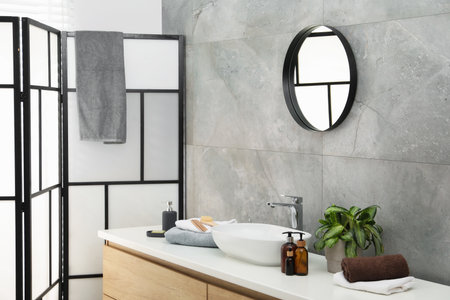 Stylish bathroom interior with mirror, folding screen and vessel sink