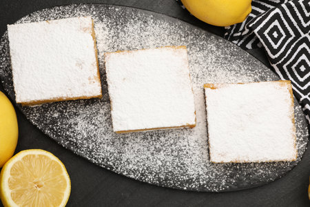 Tasty lemon bars and fresh fruits on black table, flat layの写真素材