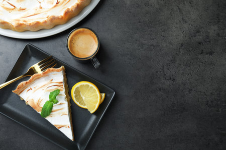 Slice of tasty lemon meringue tart with mint served on black table, flat lay. Space for textの写真素材