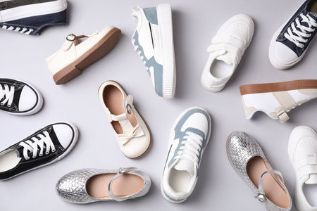 Many stylish kid's shoes on gray background, flat lay