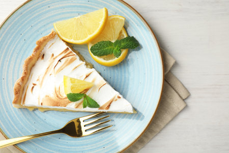 Slice of tasty lemon meringue tart served on white wooden table, flat layの写真素材