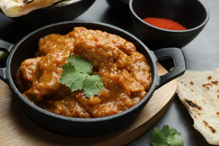 Delicious chicken tikka masala, cilantro, and paprika powder on gray textured table, closeupの写真素材