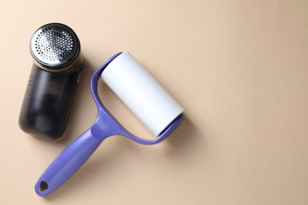 Lint roller and fabric shaver on beige background, flat lay. Space for textの写真素材
