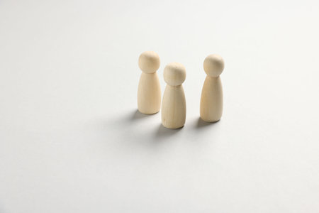Three wooden figures on white table, closeup. Space for textの写真素材