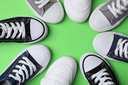 Frame of stylish kid's sneakers on green background, flat lay. Space for textの写真素材