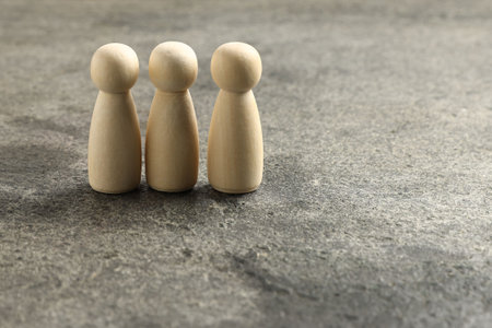 Three human figures on gray surface, closeup. Space for textの写真素材