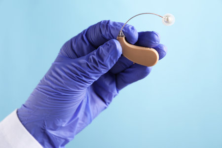 Doctor with hearing aid on light blue background, closeupの写真素材