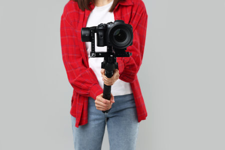 Vidographer using gimbal stabilizer with camera on light background, closeupの写真素材