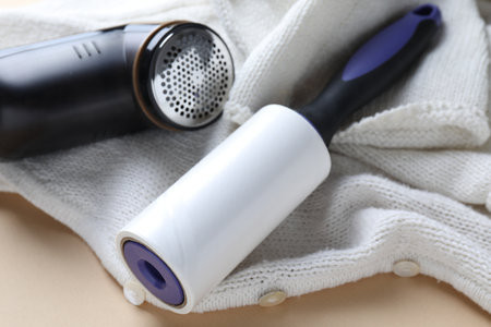 Lint roller, fabric shaver and cloth on beige background, closeupの写真素材