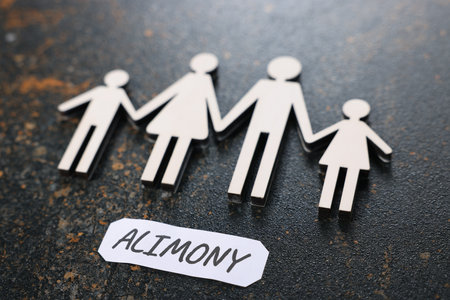 Paper note with word Alimony and figures of family on dark table, closeupの写真素材