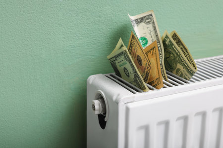 Dollar banknotes on heating radiator near green wall, closeup. Space for textの写真素材