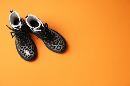 Stylish kid's boots on orange background, flat lay. Space for textの写真素材