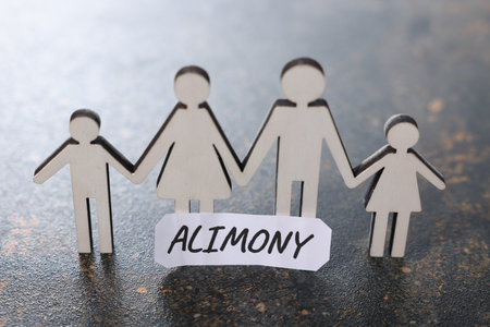 Paper note with word Alimony and figures of family on dark table, closeupの写真素材