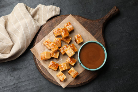 Tasty candies with salt and caramel sauce on dark textured table, top viewの写真素材