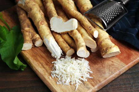 Grated horseradish, grater, leaves and fresh roots on wooden table, closeupの写真素材