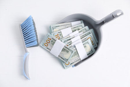 Dustpan with broom and dollar banknotes on white background, flat layの写真素材