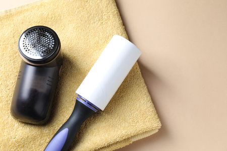 Lint roller, fabric shaver and towel on beige background, top view. Space for textの写真素材